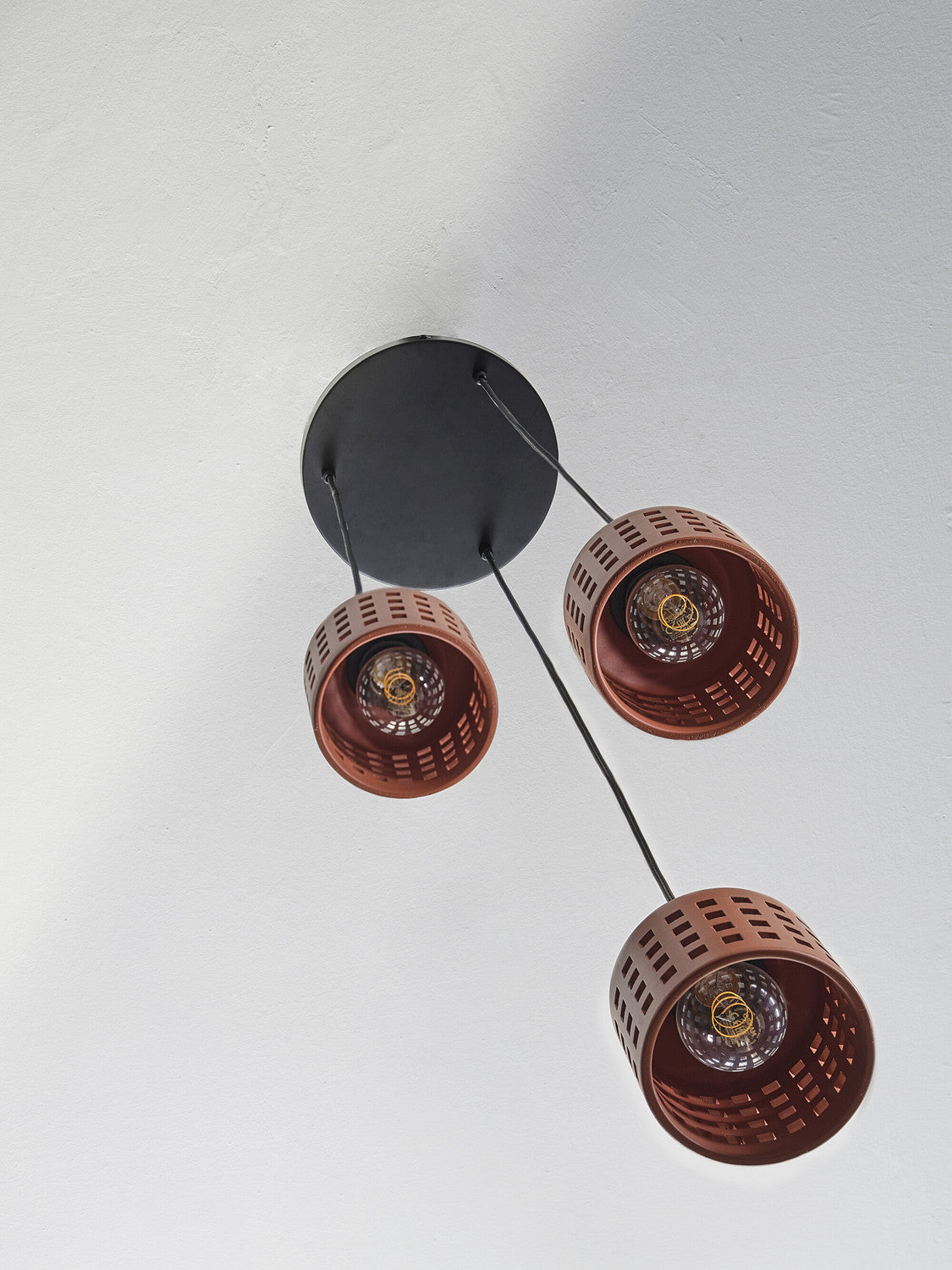 Vue du dessous du plafonnier noir et des trois suspensions avec ampoules visibles.