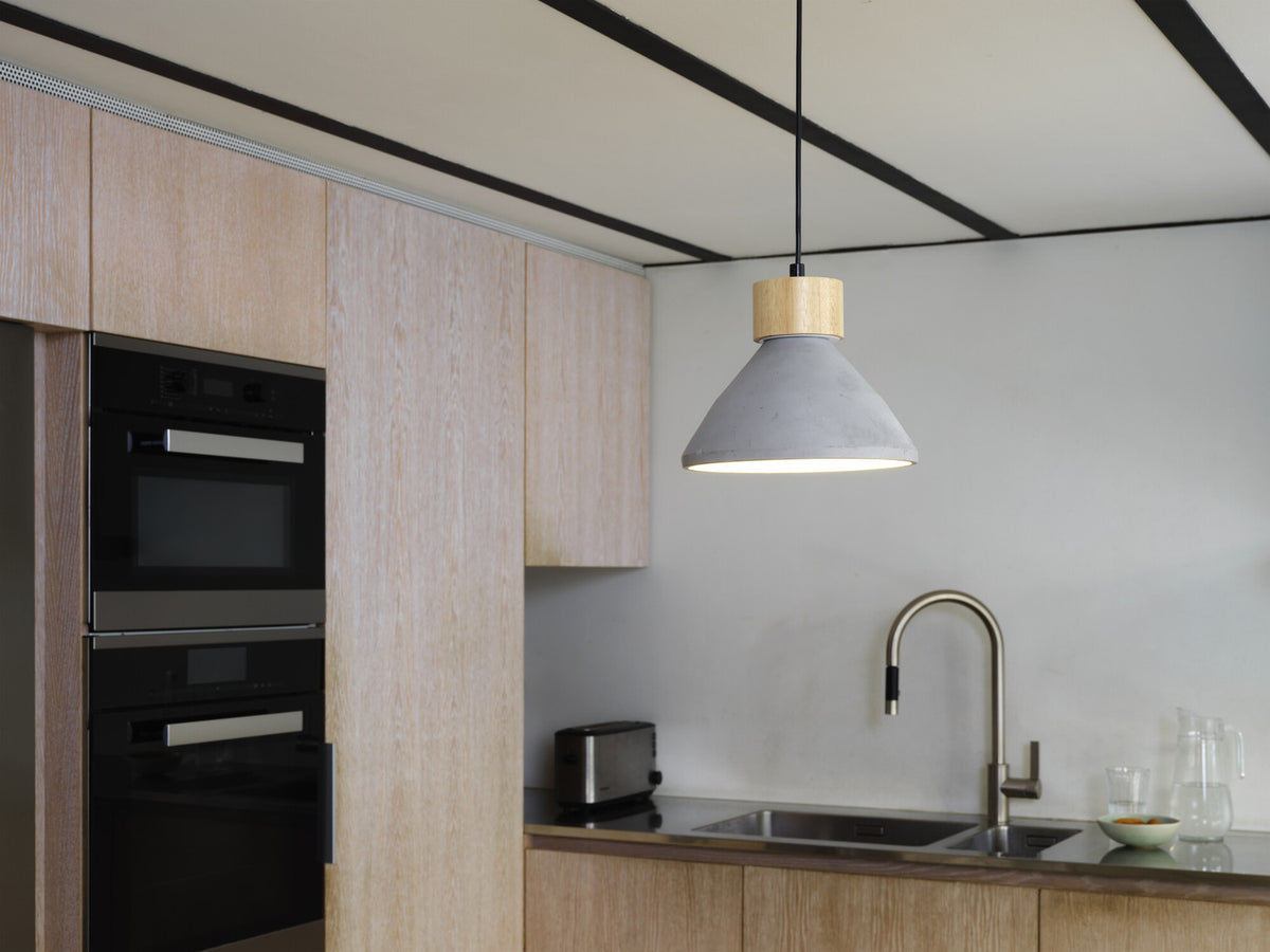 Suspension allumée au-dessus d'un évier de cuisine, dans un intérieur clair.