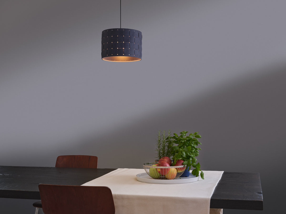 Mise en ambiance au-dessus d'une table dressée, suspension allumée et corbeille de fruits.