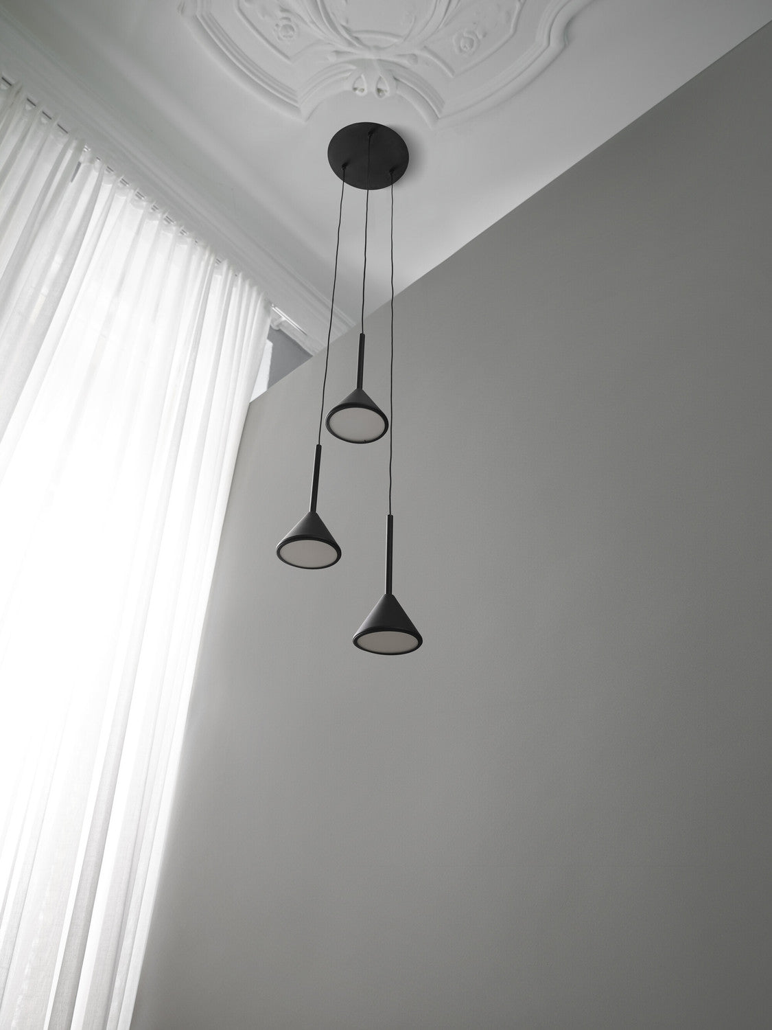 Vue en contre-plongée sous un plafond mouluré, près des rideaux