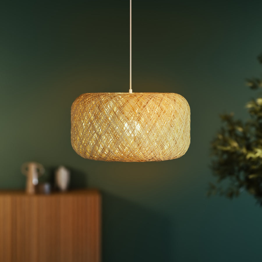 Gros plan sur l’abat-jour allumé, motif tissé et lumière chaude.
