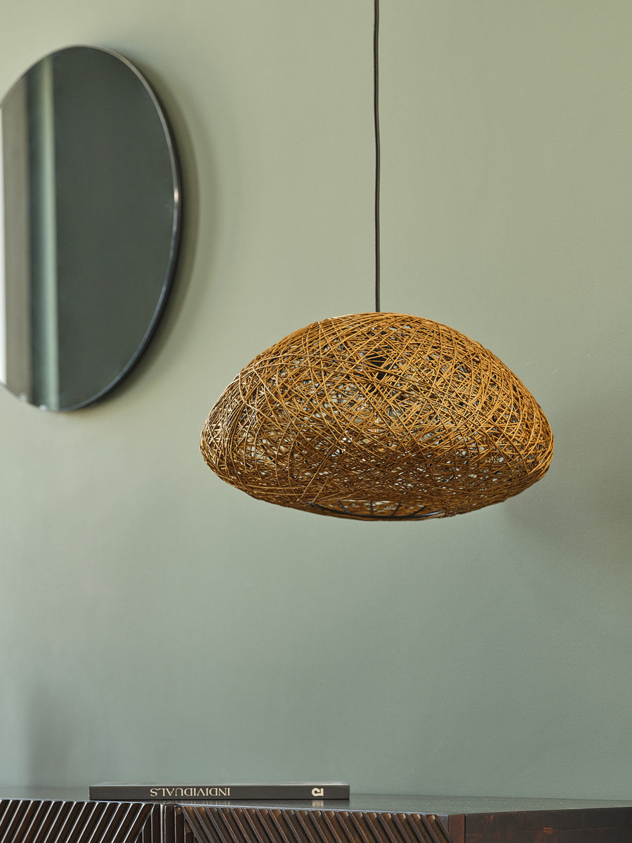 Vue rapprochée de la suspension en papier tressé devant un miroir rond.