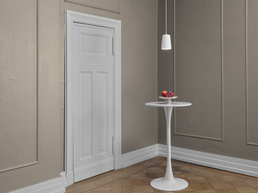 Suspension blanche suspendue au-dessus d'une table ronde dans un intérieur beige.