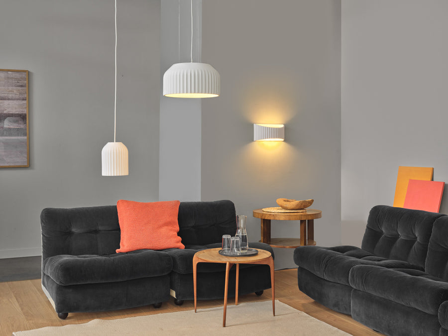 Suspension blanche au-dessus d'un canapé noir, dans un salon gris lumineux