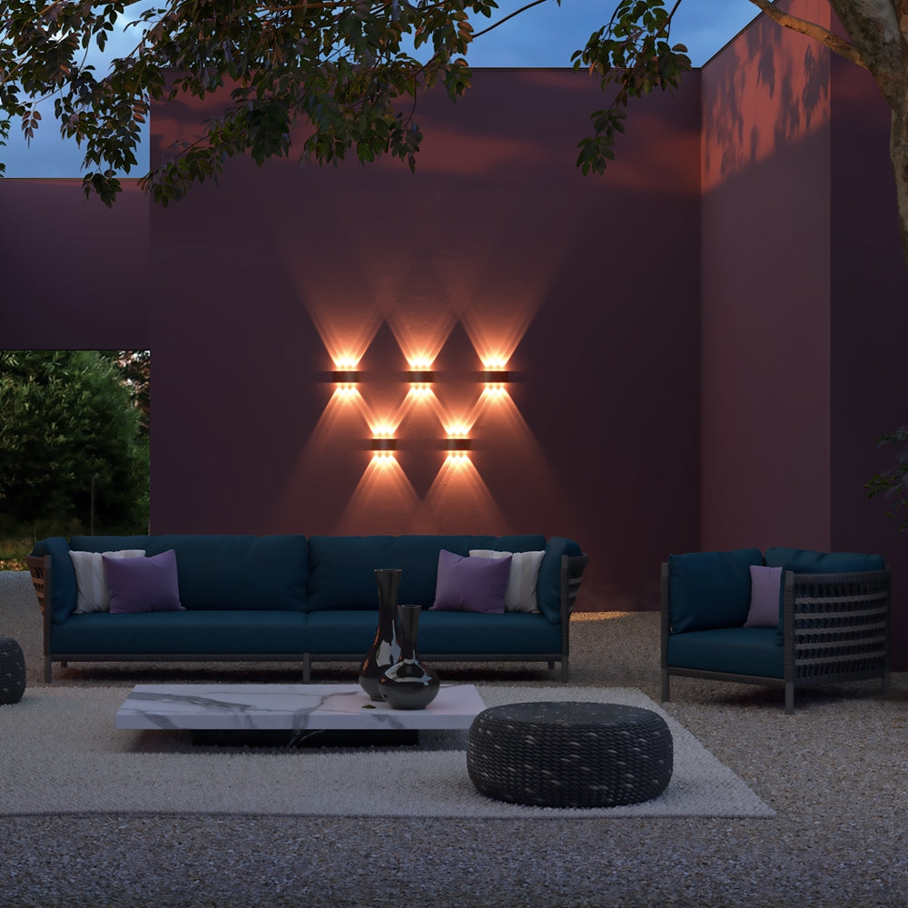 Mise en ambiance nocturne, plusieurs appliques murales éclairant un mur violet de terrasse
