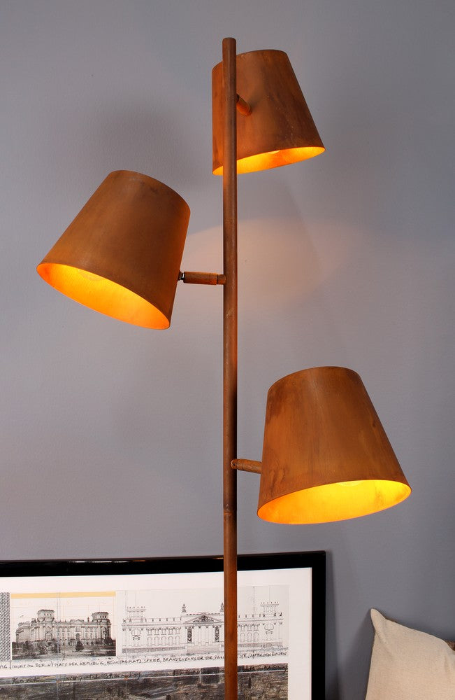 Vue rapprochée du lampadaire, trois abat-jours orientables en métal rouillé et tige verticale.
