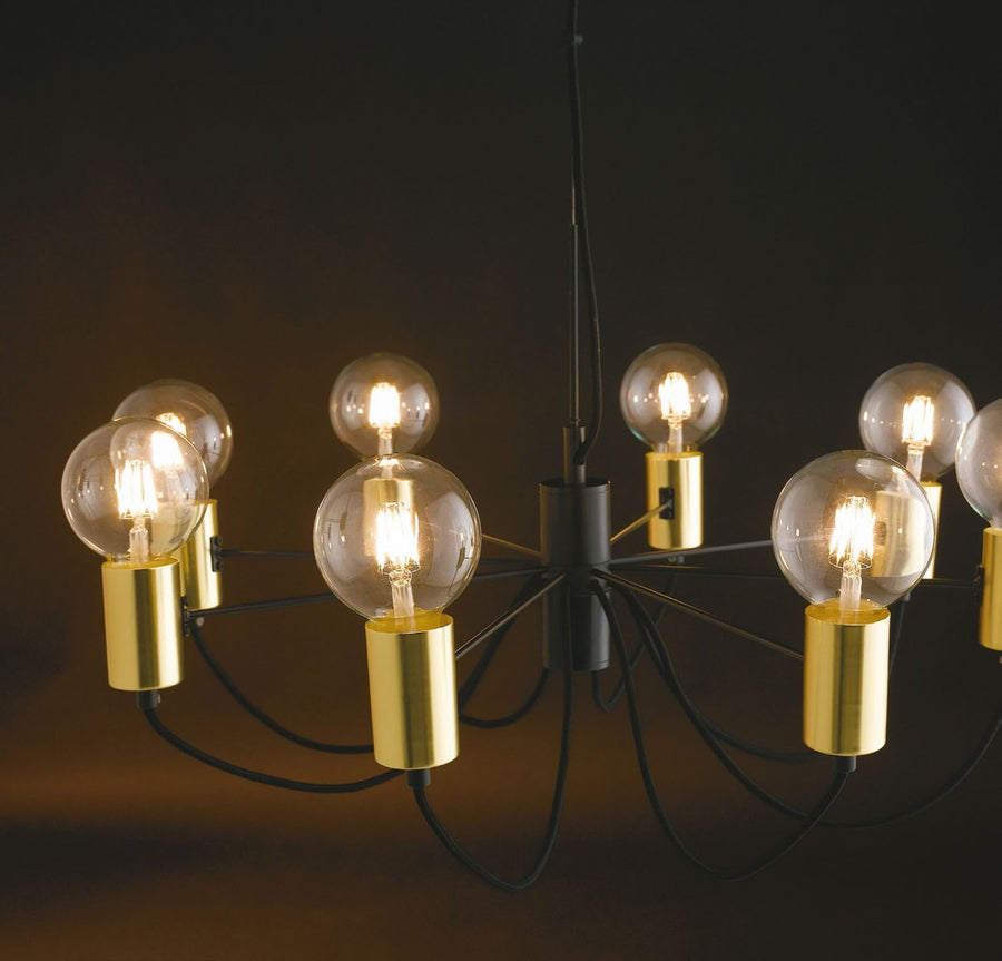 Luminaire allumé dans une pièce sombre, ampoules boules diffusant une lumière chaude et dorée.