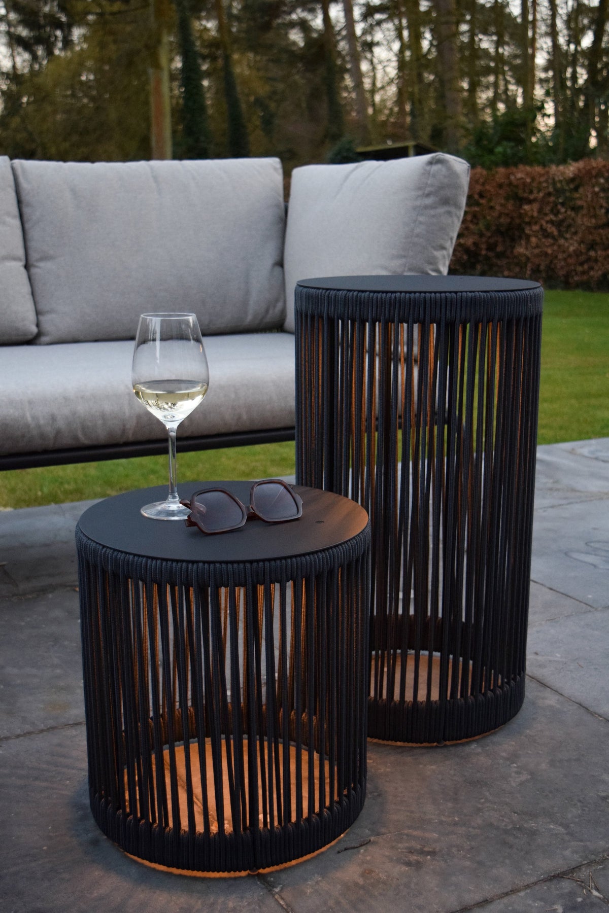 Mise en ambiance extérieure avec deux lampes posées sur une terrasse près d'un canapé.