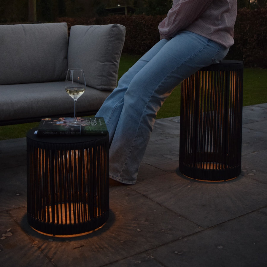 Scène de vie nocturne, personne assise sur une lampe allumée près d'un canapé.