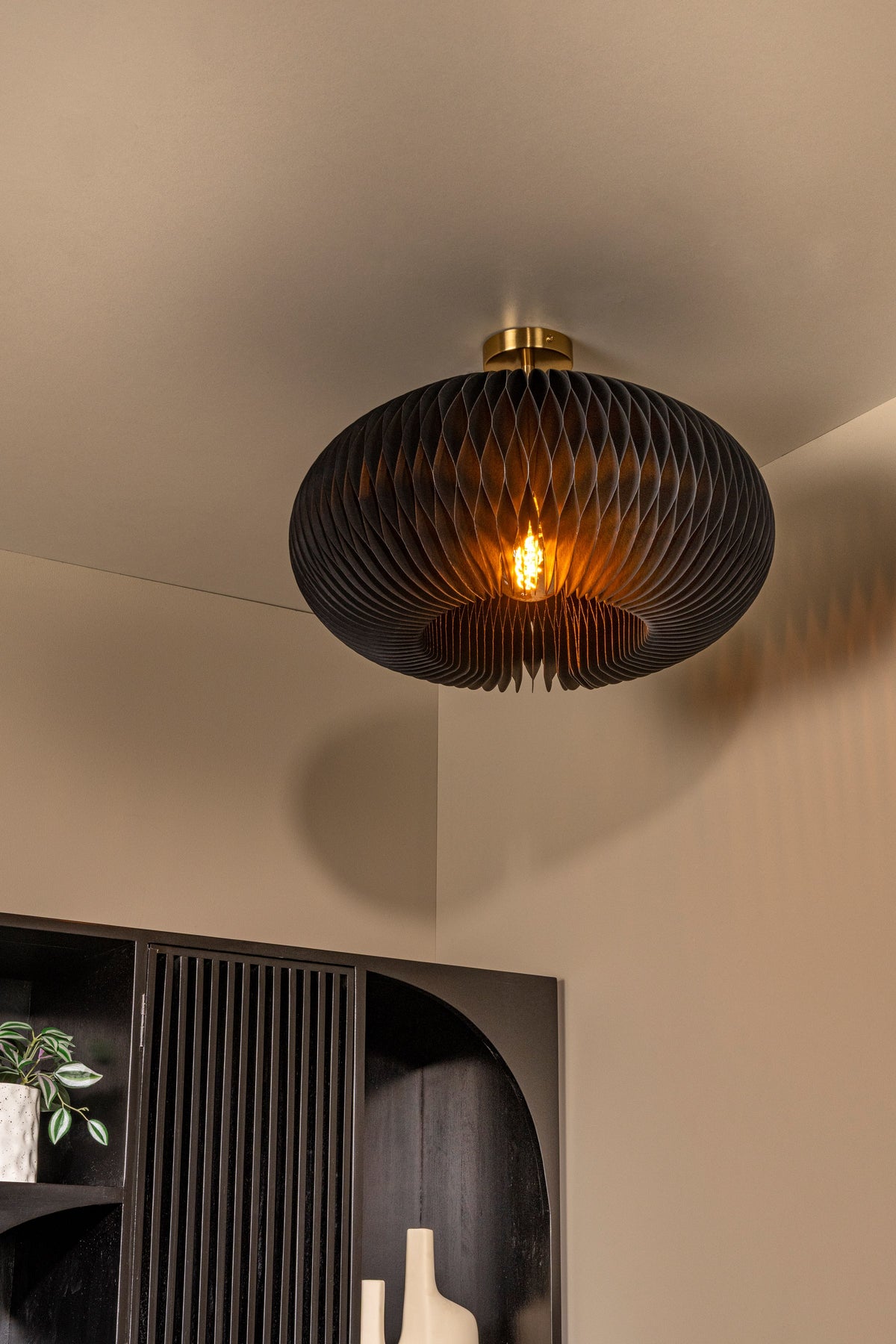 Mise en ambiance du luminaire allumé dans un intérieur sombre avec étagère noire