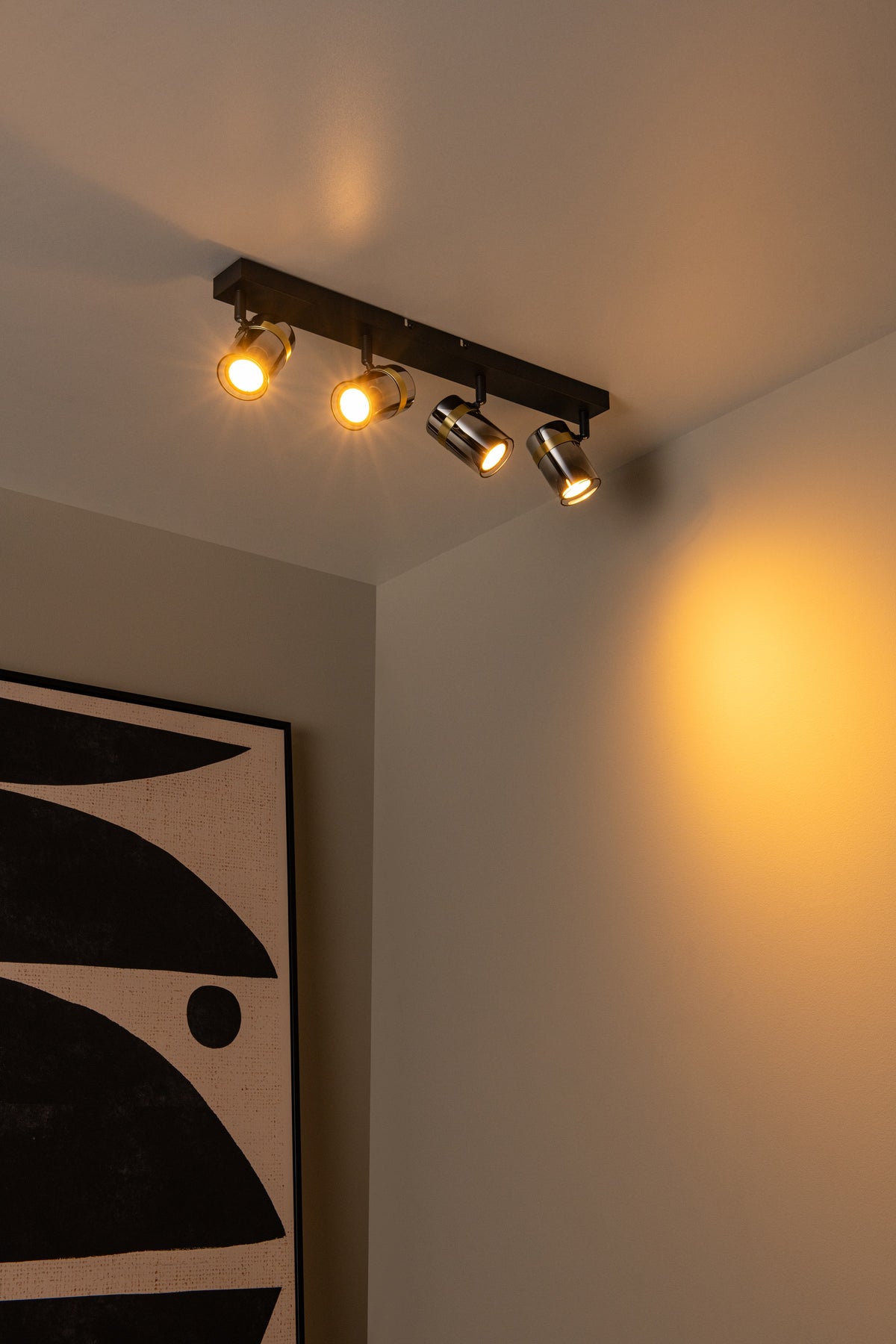 Mise en ambiance au plafond, halos dorés projetés sur le mur et tableau