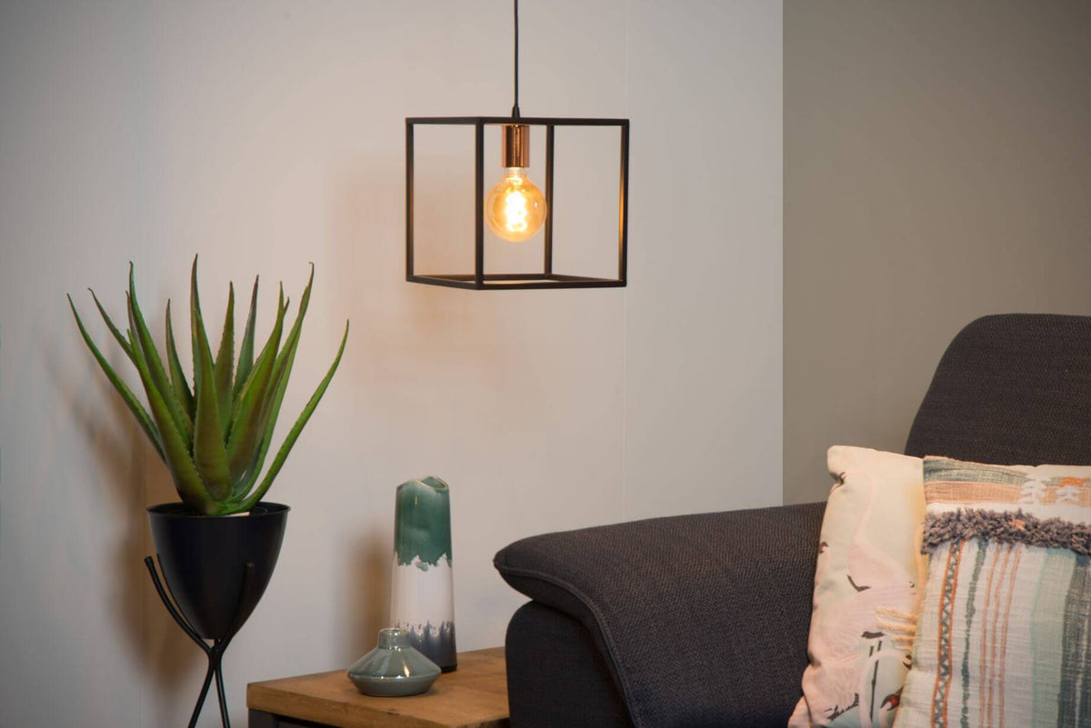 Ambiance chaleureuse avec la suspension noire allumée près d'un aloès et de coussins