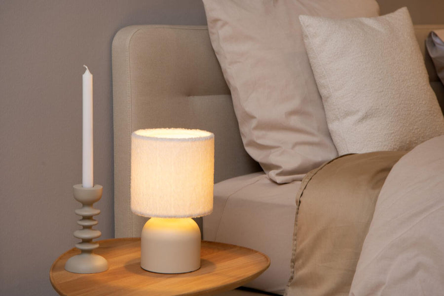 Vue rapprochée de la lampe allumée près d'un bougeoir et de coussins beiges