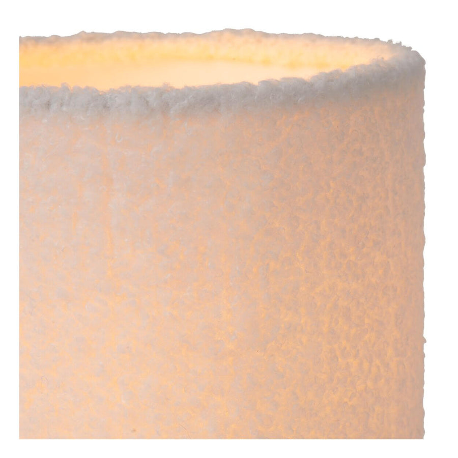 Détail du tissu bouclé de l'abat-jour, texture moelleuse et lumière chaude