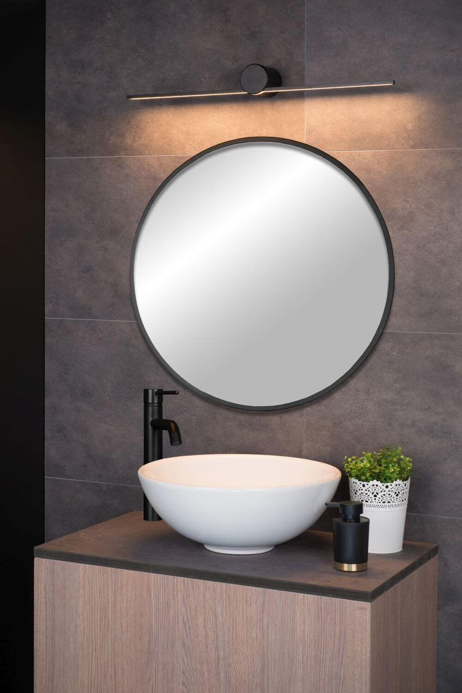 Vue rapprochée de l'applique noire au-dessus d'un miroir rond et d'une vasque blanche