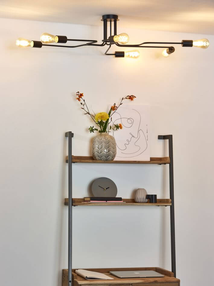 Plafonnier noir allumé au-dessus d'une étagère en bois et d'un vase fleuri