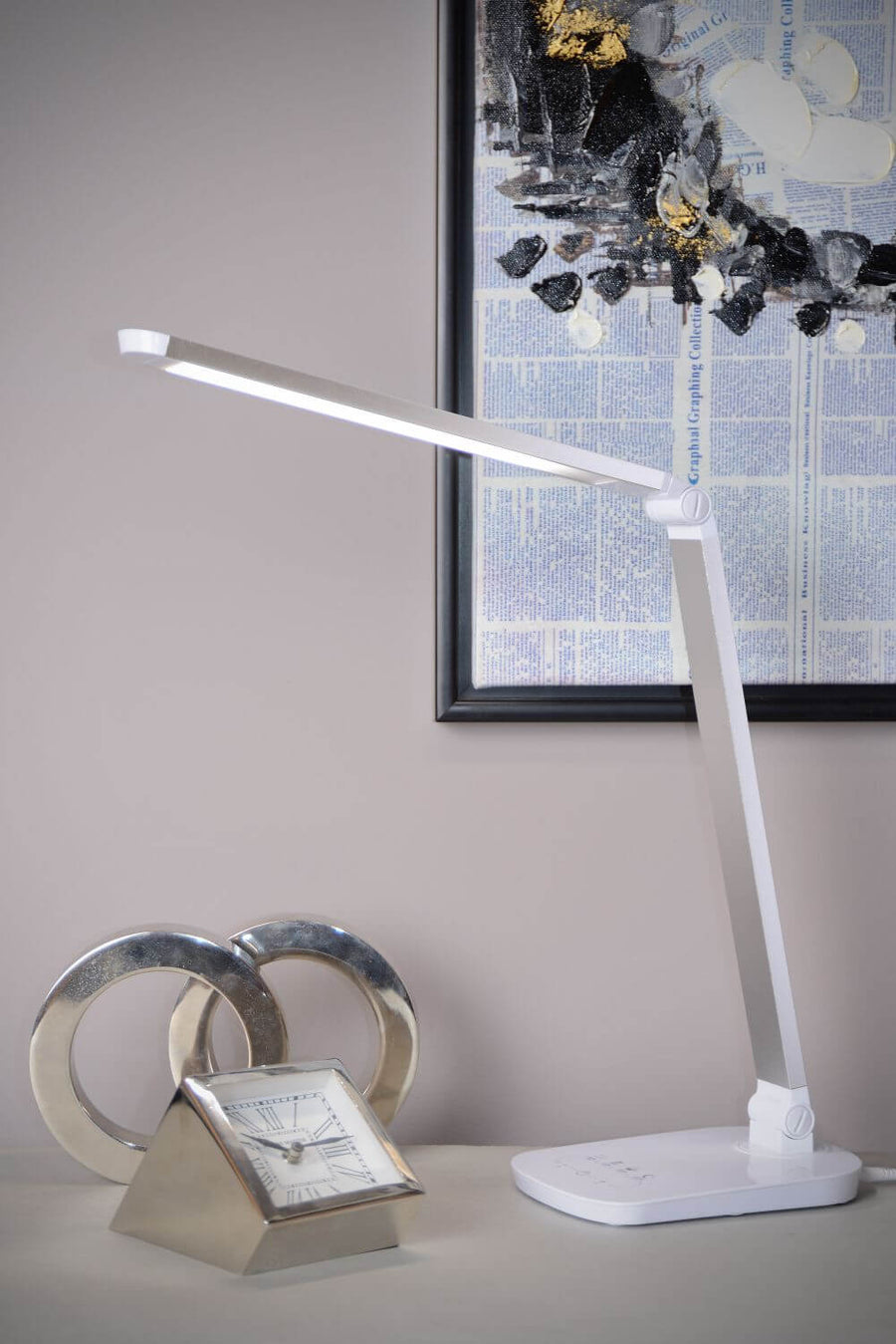 Vue rapprochée de la lampe blanche en situation, près d'une horloge et d'une œuvre encadrée