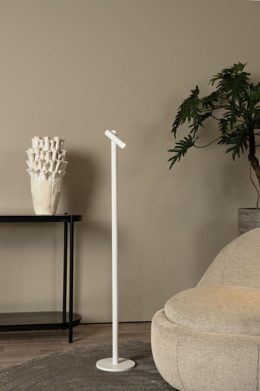 Vue en situation du lampadaire blanc devant un mur beige avec console noire.