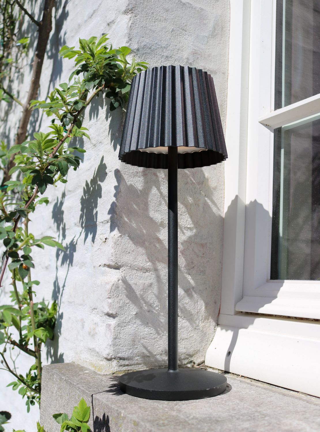 Mise en ambiance extérieure devant un mur chaulé et une fenêtre, ombres marquées.
