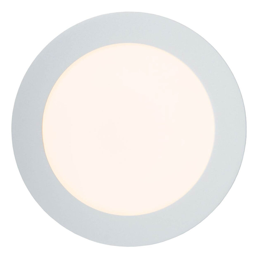 Vue de face du plafonnier allumé, diffuseur rond blanc et halo lumineux.