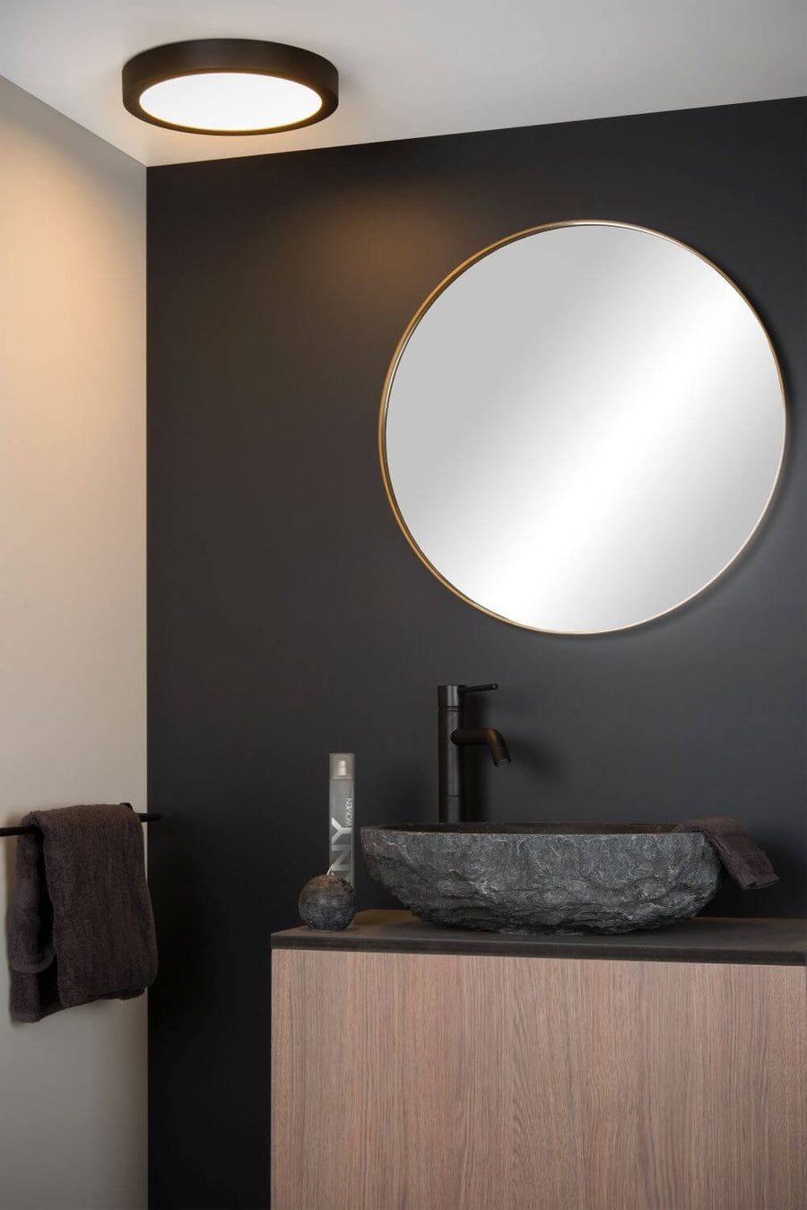 Vue rapprochée du plafonnier noir installé au-dessus d'un lavabo en pierre