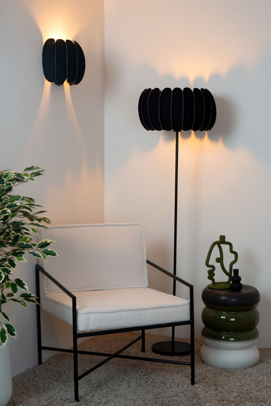 Plan rapproché du fauteuil blanc et de l'applique murale noire allumée sur le mur.