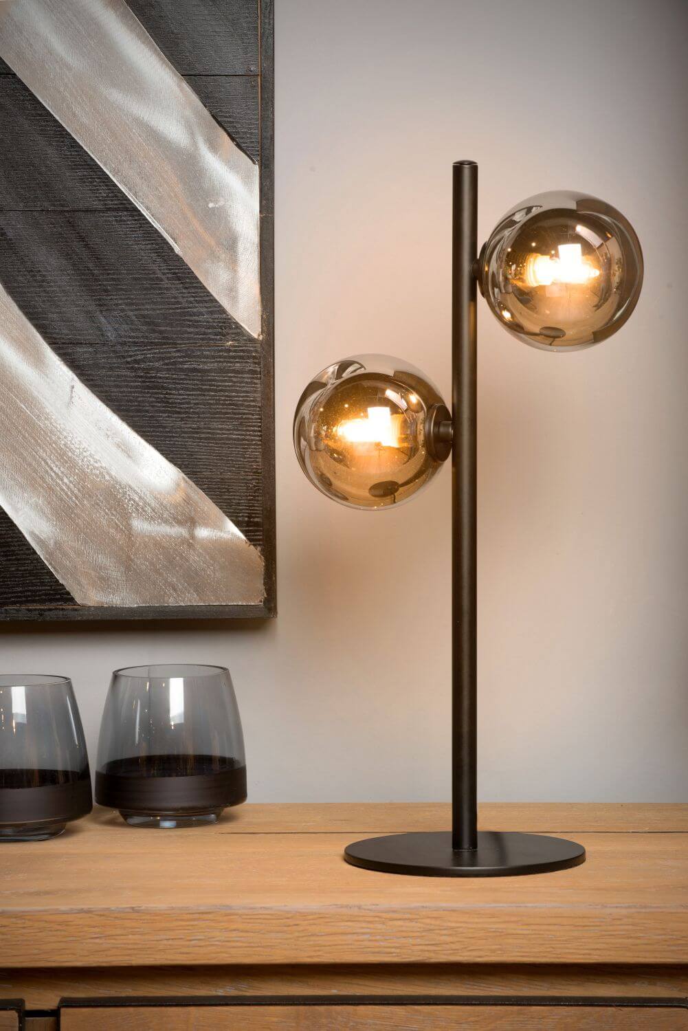 Mise en ambiance du luminaire posé sur un buffet devant un tableau