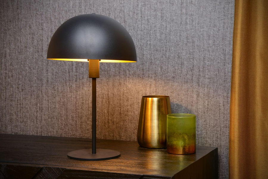 Vue rapprochée du luminaire posé sur console, abat-jour bombé diffusant une lumière dorée