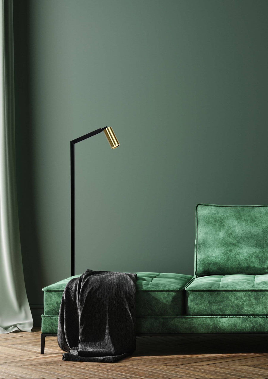 Plan large montrant le lampadaire et le canapé vert dans une pièce sombre