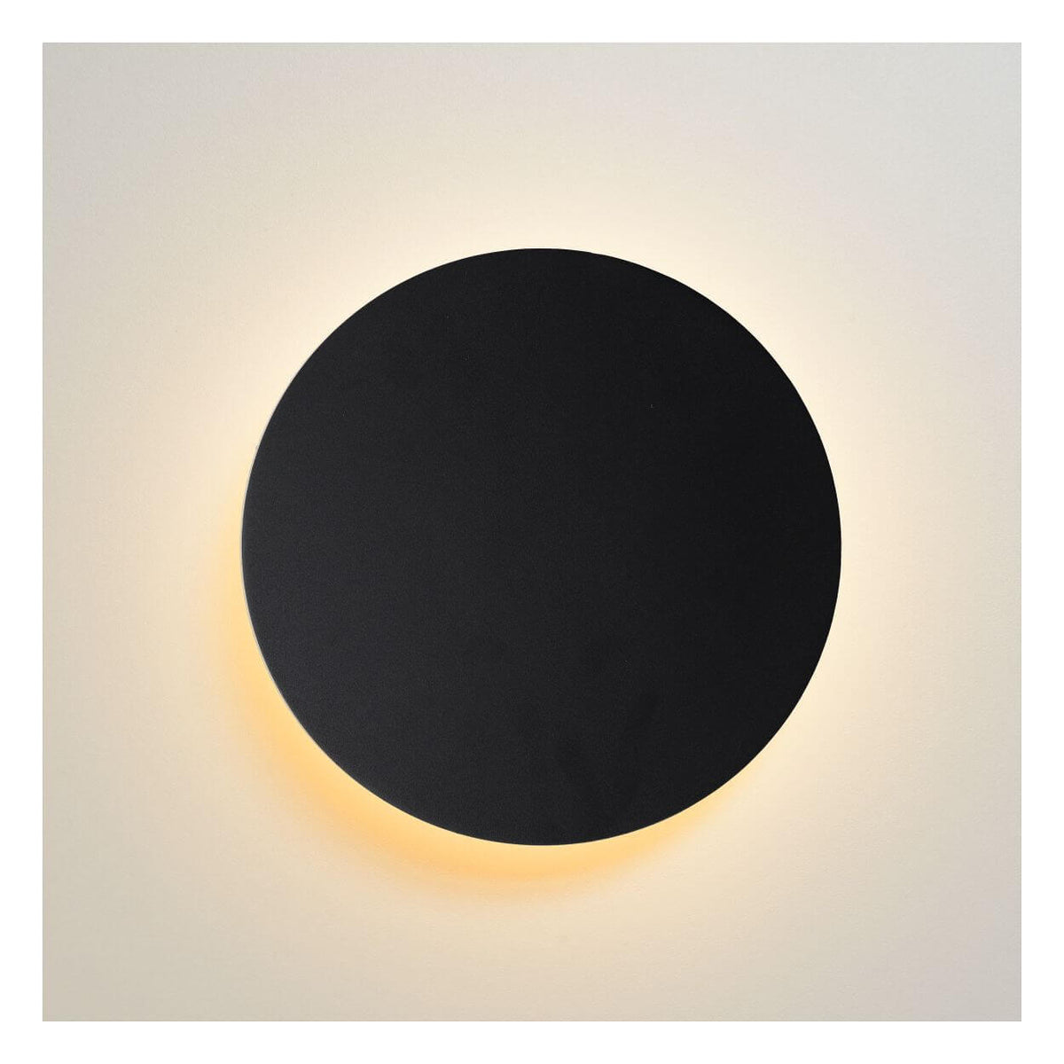 Vue de face du disque noir illuminé projetant un halo lumineux doré sur le mur