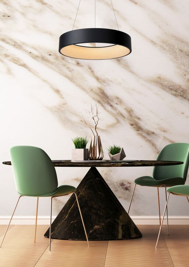 Suspension noire au-dessus d'une table ronde avec chaises vertes et mur en marbre