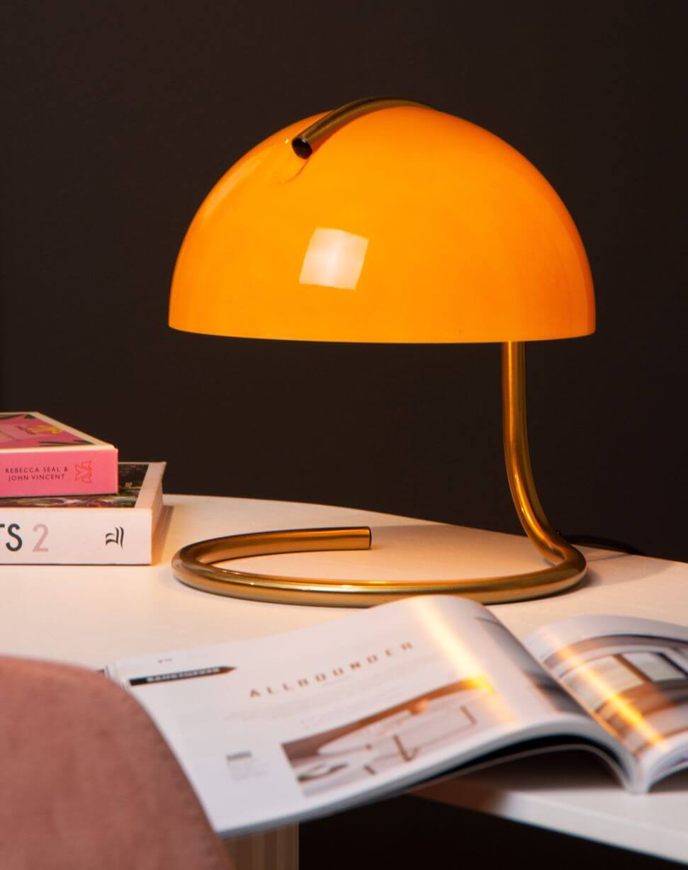 Mise en ambiance chaleureuse, la lampe éclaire un magazine ouvert