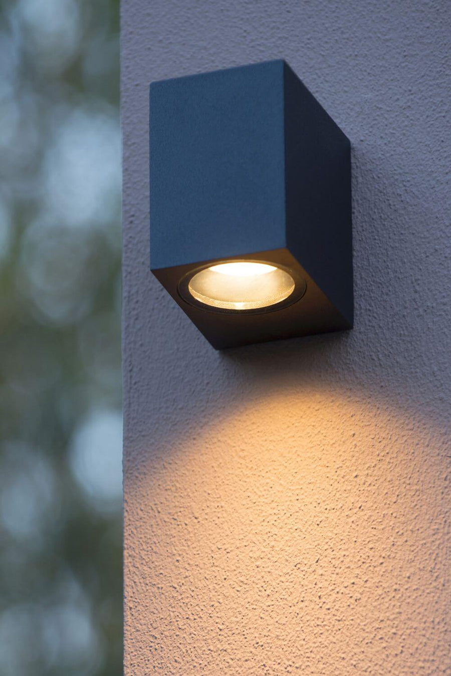 Vue rapprochée de l'applique cubique noire fixée au mur, halo lumineux chaud