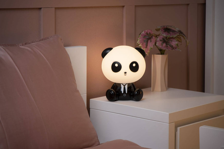 Vue rapprochée du luminaire panda allumé sur la table de nuit en bois clair