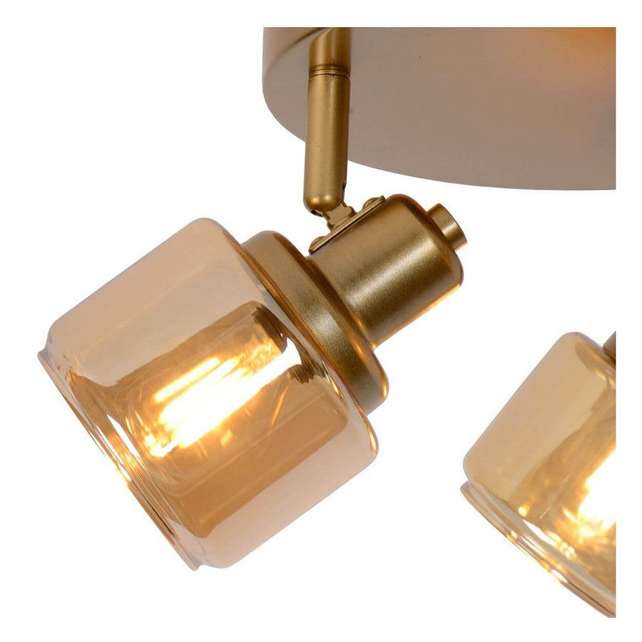 Gros plan sur un diffuseur en verre transparent et la finition dorée mate du plafonnier.