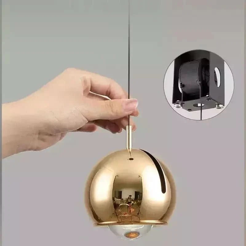 Main réglant la hauteur d'une suspension dorée avec support de plafond en médaillon
