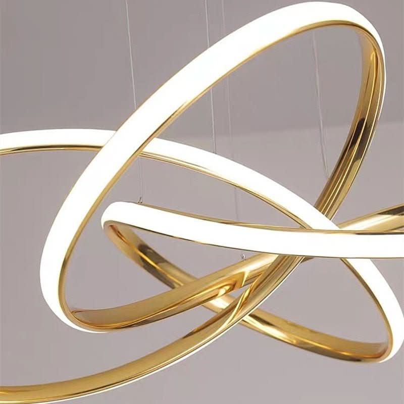 Gros plan sur les anneaux dorés entrelacés et le bandeau LED blanc du luminaire.