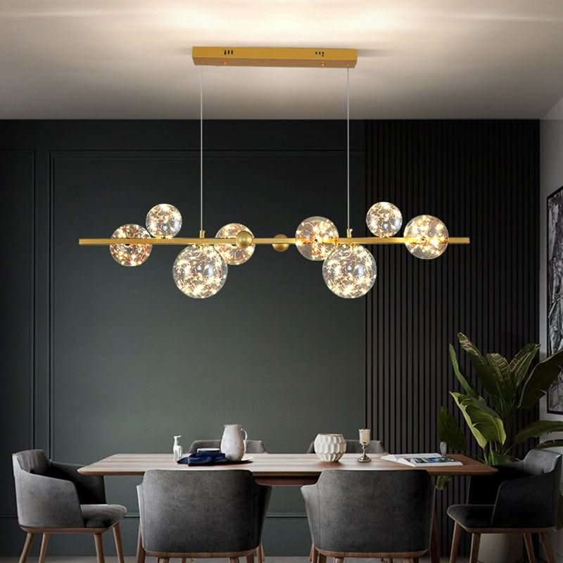 Version dorée du luminaire suspendu, salle à manger au mur vert à lattes, fauteuils gris