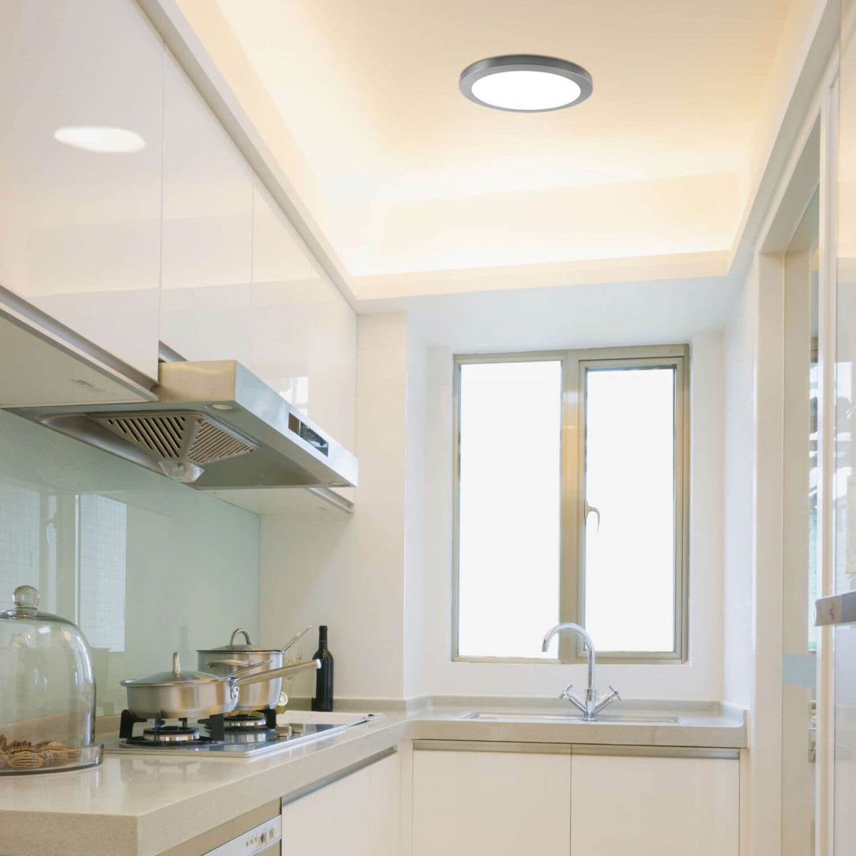 Mise en ambiance au-dessus d'une cuisine moderne blanche, plafonnier chromé allumé