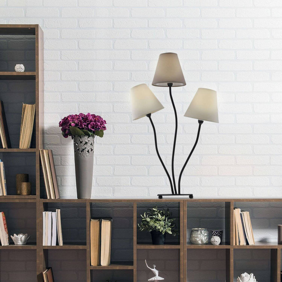 Lampe posée sur étagère en bois, mur briques blanches, livres et vase de fleurs.