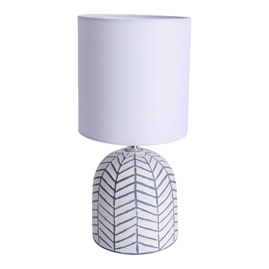 Lampe à poser blanche de face sur fond blanc, abat-jour cylindrique en tissu et base céramique