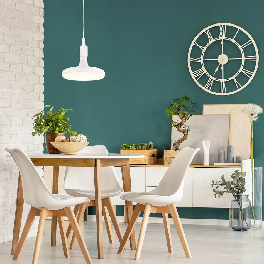 Suspension blanche allumée dans une salle à manger, mur vert bouteille et horloge murale