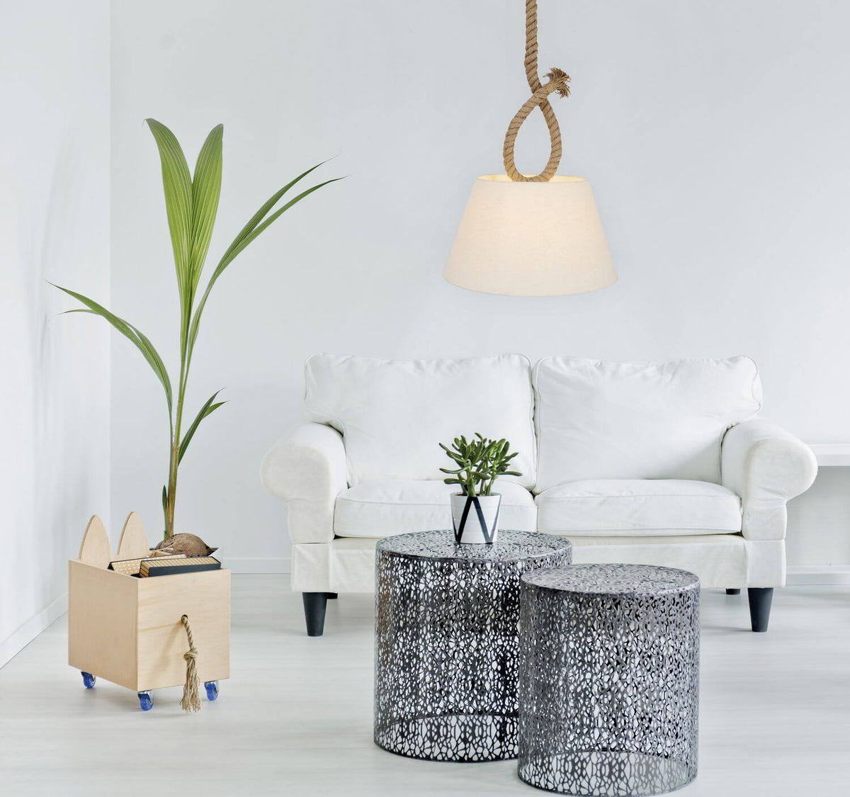 Mise en ambiance d'une suspension en corde dans un salon blanc avec canapé et plante.