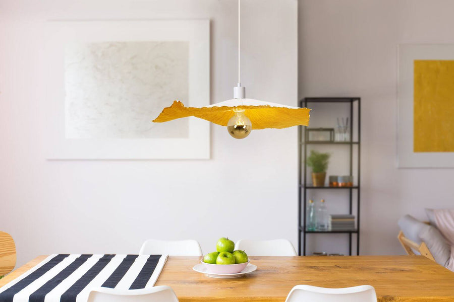Suspension éclairée au-dessus d'une table en bois dans une salle à manger claire