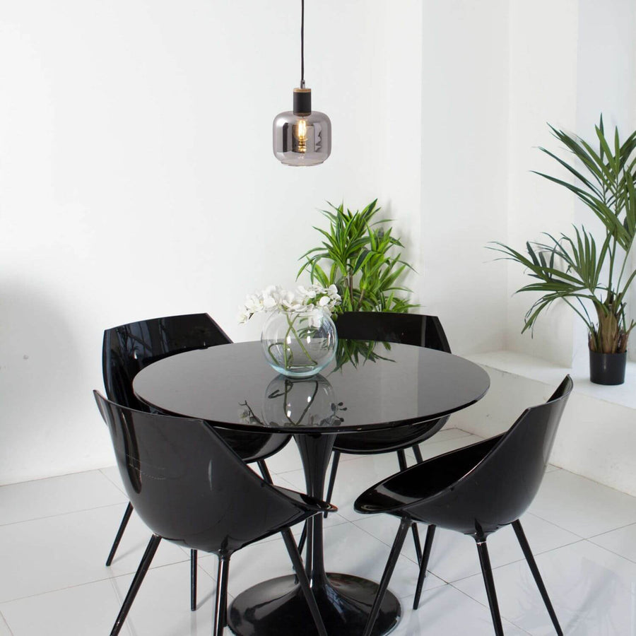 Suspension allumée au-dessus d'une table ronde noire dans un intérieur