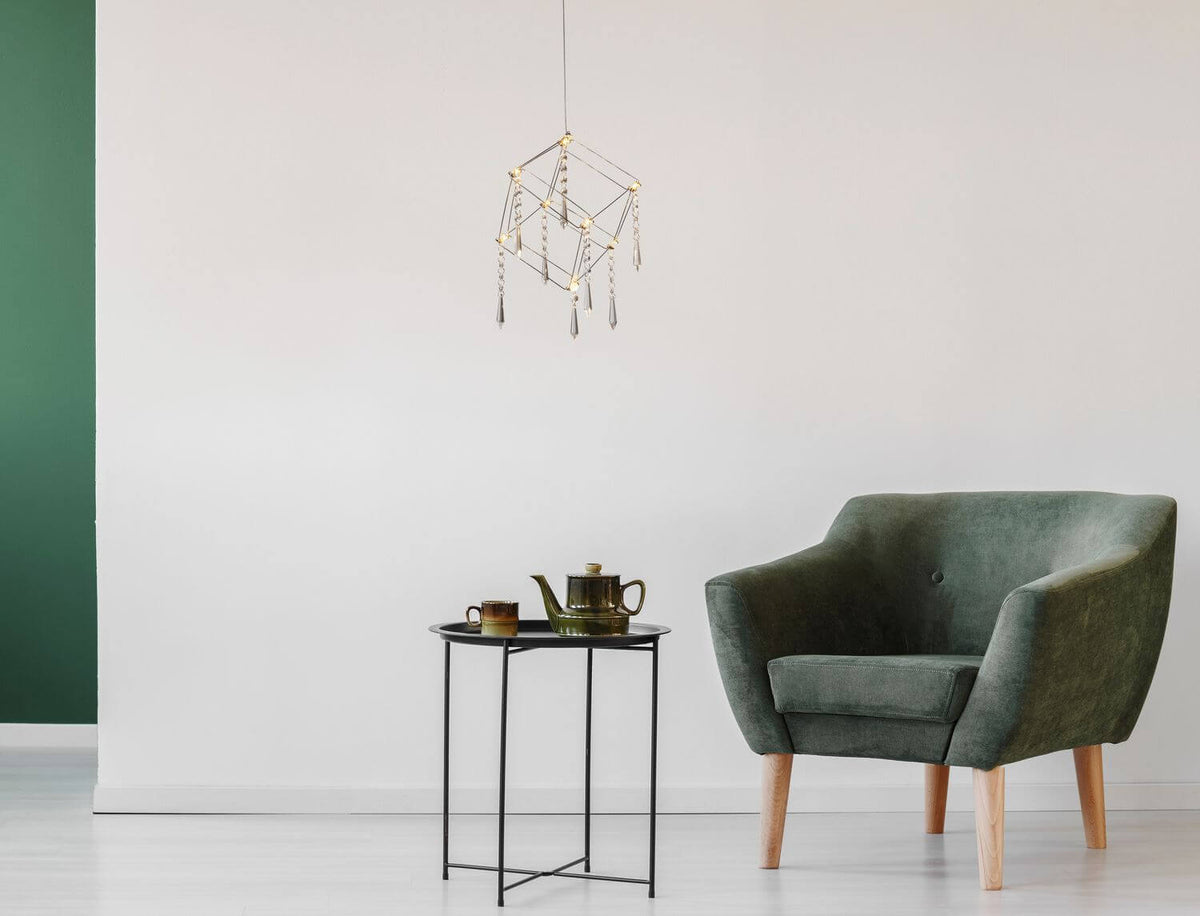 Luminaire suspendu au-dessus d'une table d'appoint dans un intérieur vert et blanc