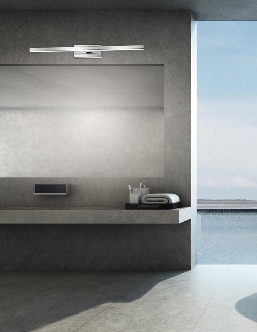Applique chromée allumée au-dessus d'un miroir de salle de bain contemporaine