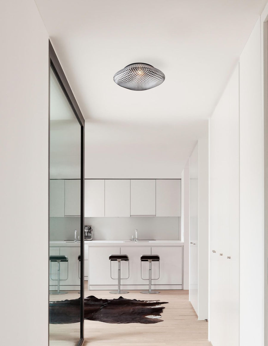Plafonnier en verre fumé fixé au plafond d'une cuisine blanche minimaliste avec îlot central