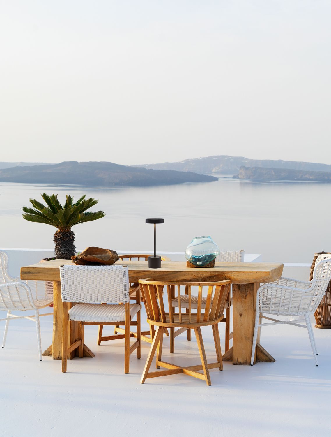 Lampe noire sans fil sur une table en bois, avec vue sur la mer au loin.