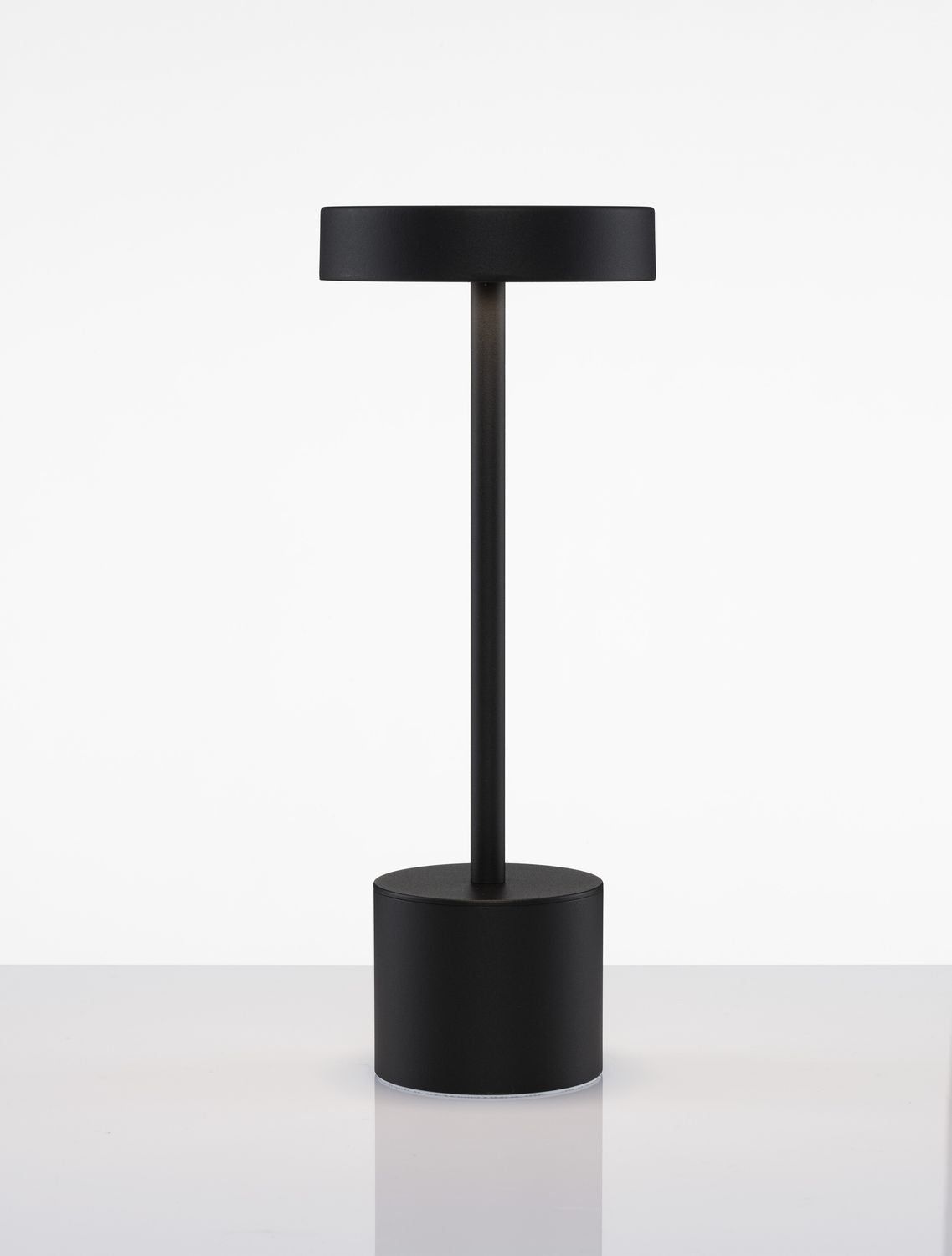 Produit noir présenté de face, socle rond et pied vertical sur surface réfléchissante.